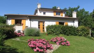 a white house with pink flowers in the yard at La Casa Dei Boschi in San Marino