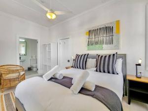um quarto com uma grande cama branca com almofadas listradas em Exquisite and Homely Apartment, Private Balcony em Cidade do Cabo