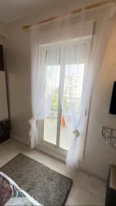 a bedroom with a window with white curtains and a rug at Spacious appartement of two rooms close to morocco mall in Casablanca