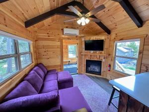 een woonkamer met een paarse bank en een open haard bij BMV6 Tiny Home village near Bretton Woods in Twin Mountain