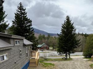 a house with a staircase next to a tree at BMV6 Tiny Home village near Bretton Woods in Twin Mountain