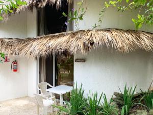 a table and chairs sitting outside of a building with a thatch roof at Surfbreak B&B in Cabarete