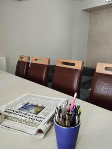 a table with a newspaper and a cup of pens at Angelo Apartment 4 karavomylos in Karavomylos