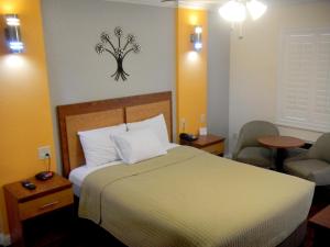 um quarto de hotel com uma cama e duas cadeiras em FairBridge Inn & Suites Gateway to Yosemite em Merced