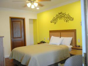 a bedroom with a bed with a yellow wall at FairBridge Inn & Suites Gateway to Yosemite in Merced