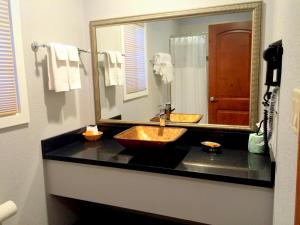 a bathroom with a sink and a large mirror at FairBridge Inn & Suites Gateway to Yosemite in Merced