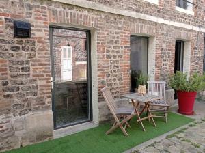a patio with a table and two chairs next to a brick building at Gîte Quai N 10 in Saint-Valery-en-Caux
