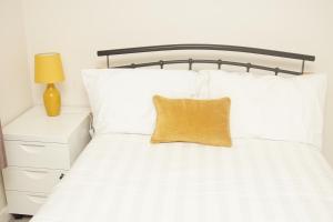 a white bed with a yellow pillow on it at Deluxe City Centre 4 Bedroom Entire Town House in Leeds