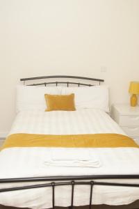 a bedroom with a bed with a yellow pillow on it at Deluxe City Centre 4 Bedroom Entire Town House in Leeds