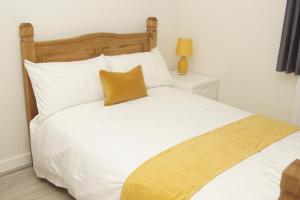 a white bed with a yellow pillow on top of it at Deluxe City Centre 4 Bedroom Entire Town House in Leeds