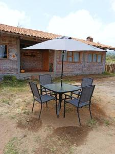 een tafel met twee stoelen en een parasol bij Hermosa cabaña en zacatlan puebla la escondida in Jicolapa