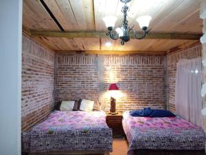 een slaapkamer met 2 bedden en een bakstenen muur bij Hermosa cabaña en zacatlan puebla la escondida in Jicolapa