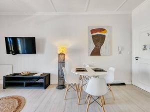 una sala de estar blanca con mesa y sillas en Contemporary and Stylish Apartment in Observatory en Ciudad del Cabo
