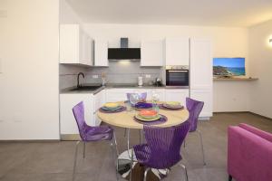 uma cozinha com uma mesa de madeira e cadeiras roxas em Appartamento Casa vacanza Le Terrazze Via Parigi,23 em Castelsardo