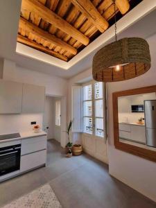 a kitchen with white cabinets and a ceiling with wooden beams at Apartamento rústico-modernizado in Blanes