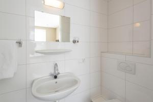 a white bathroom with a sink and a mirror at Hof van Renesse in Noordwelle