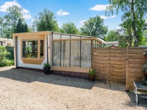 a tiny house with glass walls and a wooden fence at Chalet in Grenspark Kalmhoutse Heide near Antwerp in Putte