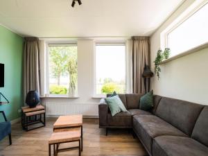 uma sala de estar com um sofá castanho e duas janelas em Cozy holiday home in Oploo in a wonderful environment em Oploo