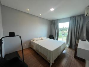 1 dormitorio con cama y ventana grande en Duplex em Guarapari com piscina privativa!, en Guarapari