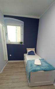 - une chambre dotée d'un lit avec un mur bleu dans l'établissement Apartment Błękitny, à Carolinensiel