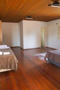 a room with two beds and a wooden floor at Casa com piscina e churrasqueira em Lagoa Santa MG in Lagoa Santa