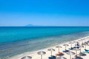 eine Reihe von Sonnenschirmen am Strand mit dem Meer in der Unterkunft Boutique Giannikis By The Beach in Limenaria