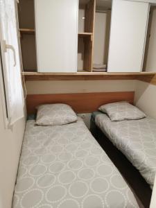 two beds in a small room with shelves at Mobil-home in Foix