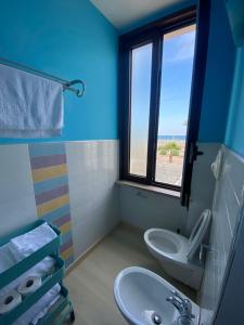ein Bad mit einem Waschbecken, einem WC und einem Fenster in der Unterkunft La perla nera in Margherita di Savoia