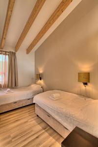 two beds in a room with wooden floors at Najade Resort Het Gooi in Eemnes