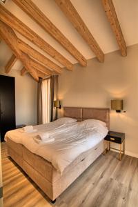 een groot bed in een slaapkamer met houten plafonds bij Najade Resort Het Gooi in Eemnes