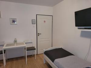 Cette chambre comprend un lit, un bureau et une télévision. dans l'établissement Pokoje Gościnne Galeon, à Darłowo