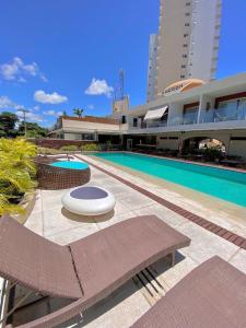 uma piscina ao lado de um grande edifício com um edifício em Flats em Salvador à 150m da praia em Salvador