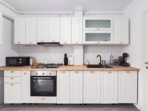 een keuken met witte kasten en een zwarte oven bij Bohemian Bliss in Sibiu