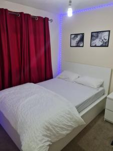a bedroom with a white bed with a red curtain at SOFT PILLOW in North Woolwich