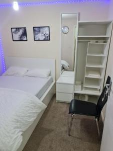 a bedroom with a white bed and a chair at SOFT PILLOW in North Woolwich
