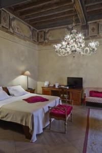 una camera con un grande letto e un lampadario a braccio di Albergo Cappello a Ravenna