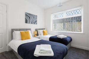 a bedroom with two beds with blue sheets and yellow pillows at Connaught House - Wi-Fi, Parking, Contractors in Preston
