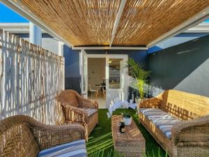 a patio with wicker chairs and a couch and a table at Visually Stunning apartment in Cape Town