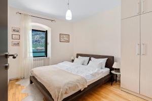 a white bedroom with a large bed with a window at Apartments Saxo in Kotor
