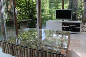 ein Wohnzimmer mit einem TV und einem Glastisch in der Unterkunft Gîte L'Orée 