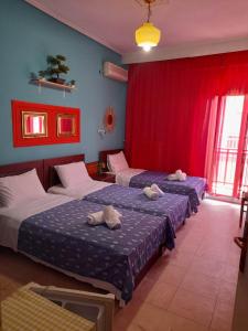 2 Betten in einem Zimmer mit roten Vorhängen in der Unterkunft Faros in Platamonas