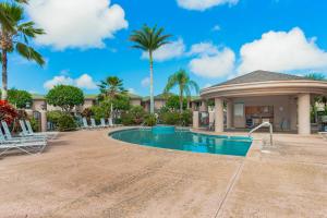 Una piscina en un resort con sillas y palmeras. en Waikoloa Fairways A108, en Waikoloa