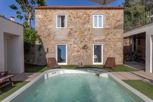 a pool in front of a building with a house at Villa Redouça in Cedrim