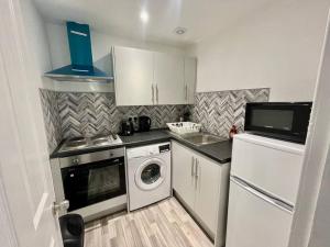 a small kitchen with white cabinets and a washer and dryer at Large 2 bed near Glasgow Airport in Paisley +12 photos