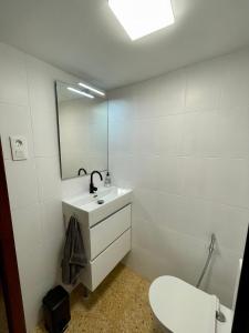 a bathroom with a sink and a toilet and a mirror at Sol y playa in Puerto de Sagunto