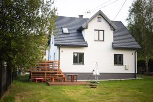 a white house with a wooden deck in the yard at Domek Breloka in Buczkowice