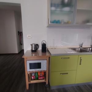 una pequeña cocina con microondas y fregadero en appartamento 'Il glicine' en Valli del Pasubio