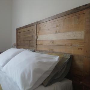 1 cama con cabecero de madera y almohada blanca en appartamento 'Il glicine' en Valli del Pasubio