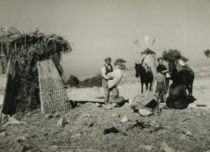 ein schwarz-weißes Foto einer Gruppe von Menschen und einer Windmühle in der Unterkunft Anemomilos Villa in Asprogerakata