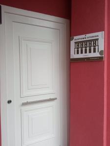 eine weiße Tür mit einem Schild an einer roten Wand in der Unterkunft Old town studios in Kavala